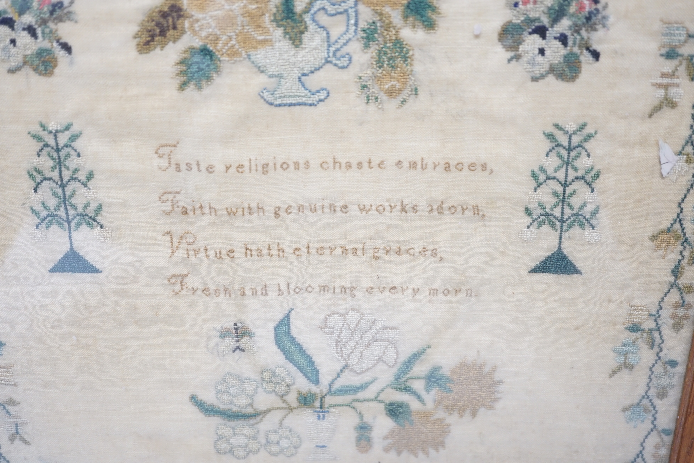 A framed sampler by Charlotte Betts, dated 1831, embroidered with a central religious verse, scrolling flowers, butterflies and birds, overall 45cm x 35cm